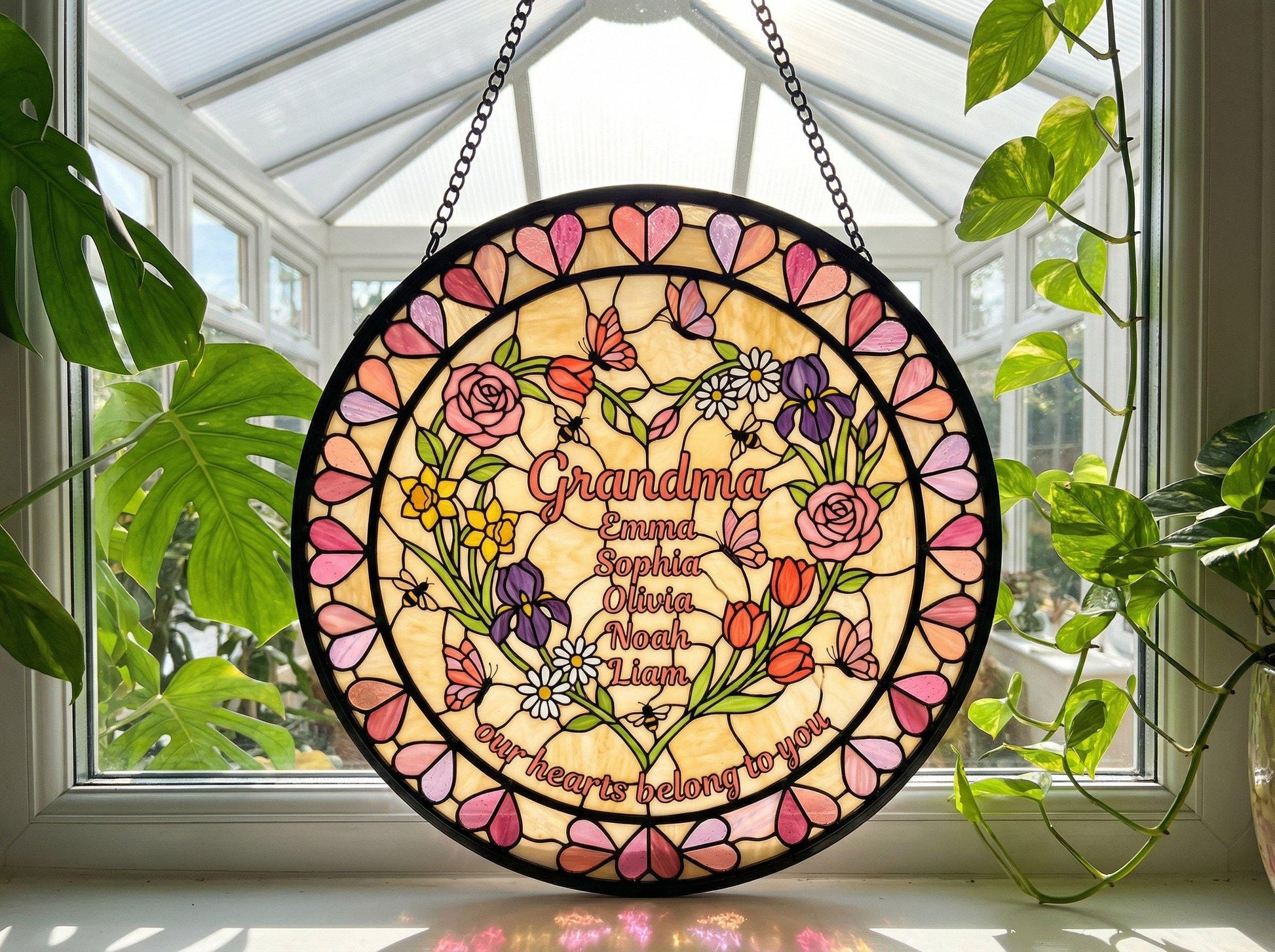 Grandma heart suncatcher hanging in white garden gazebo surrounded by pink rose bushes at golden hour