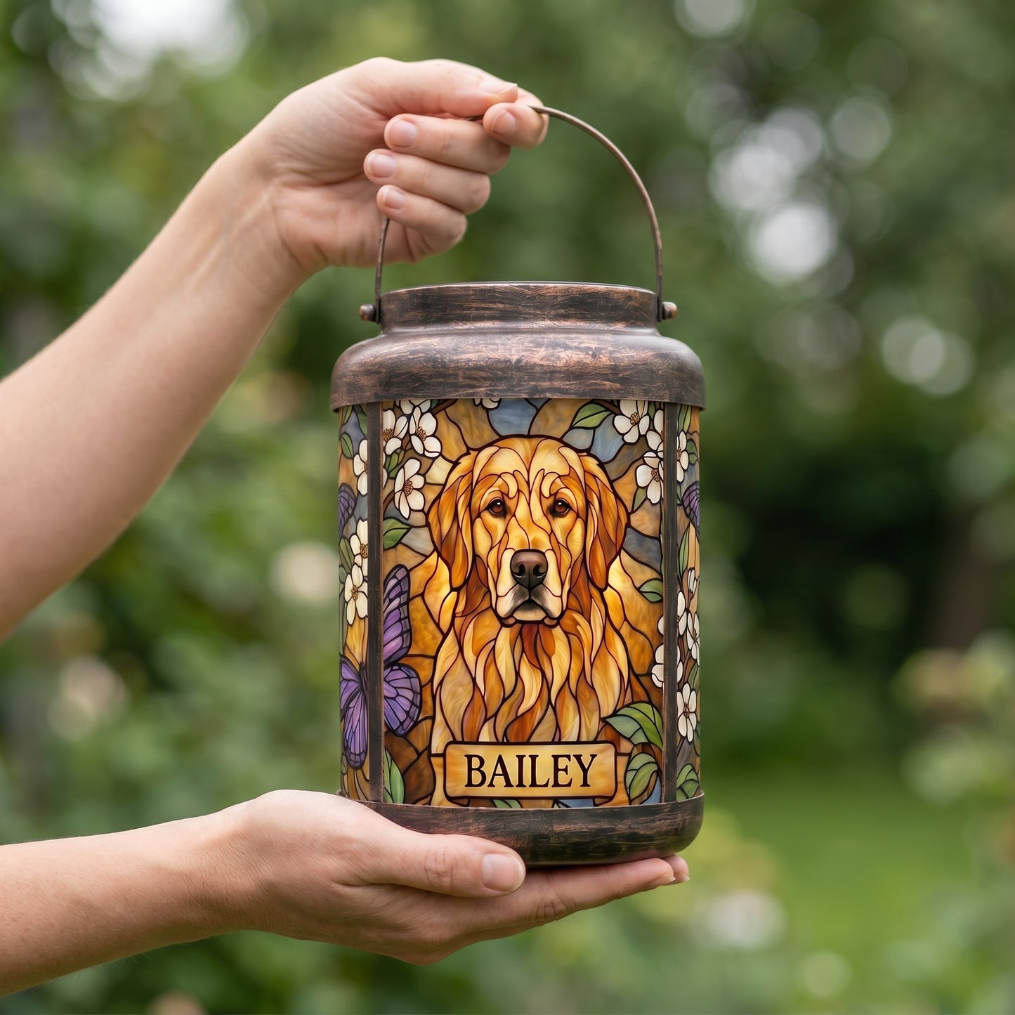 Hands holding a personalized pet memorial solar lantern outdoors to show its real size, with a custom golden retriever portrait and the name Bailey